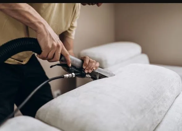 Professional steam cleaning of a couch with a carpet cleaner wand